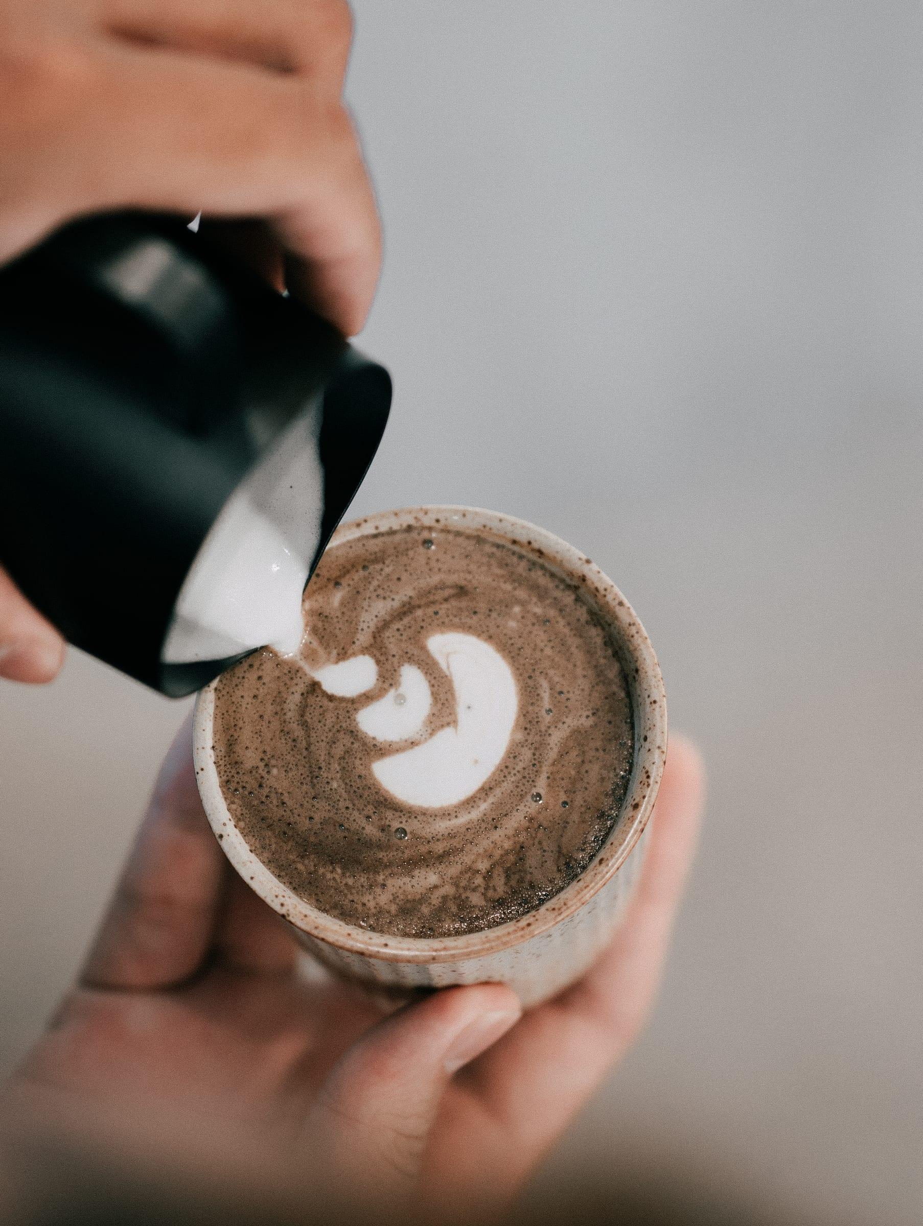 Latte art being poured into a hojicha latte